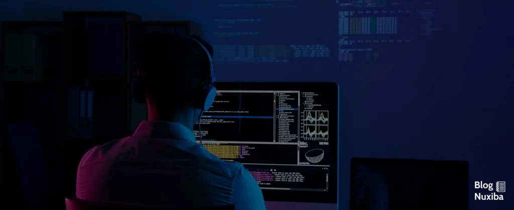 Hombre sentado frente a monitor trabajando en código con estadísticas